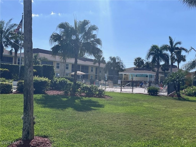 view of community featuring fence and a yard