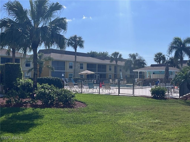 view of community featuring a yard and fence