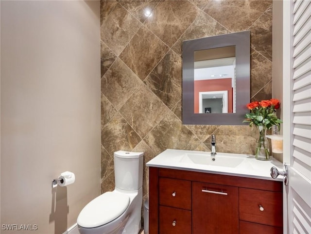 half bath featuring tasteful backsplash, tile walls, vanity, and toilet