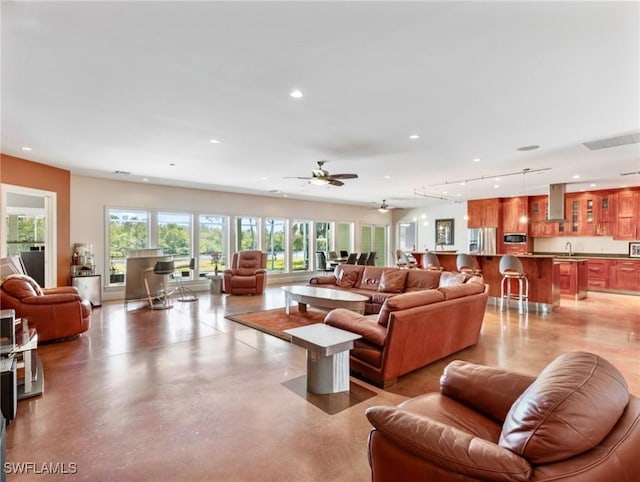 living room featuring a ceiling fan, recessed lighting, rail lighting, and finished concrete flooring