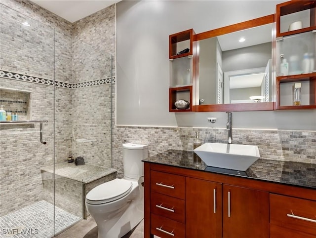 full bathroom featuring a stall shower, tile walls, toilet, and vanity