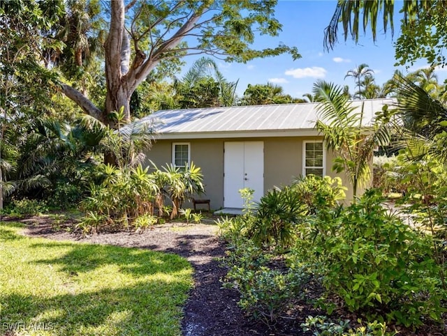 exterior space with a front yard, metal roof, and stucco siding