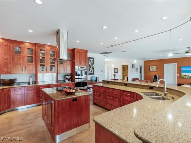 kitchen with double oven, recessed lighting, island range hood, a spacious island, and a sink