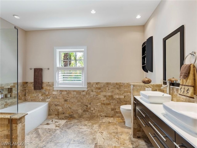 full bath featuring wainscoting, a garden tub, a sink, and tile walls