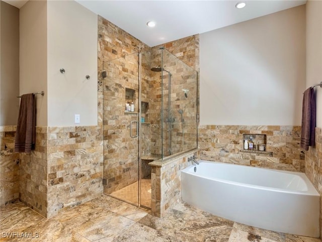 full bath featuring a stall shower, wainscoting, a bath, and tile walls