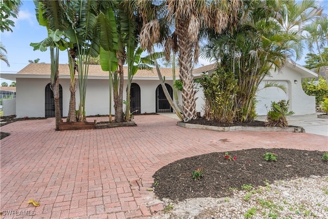 ranch-style house featuring decorative driveway, an attached garage, and stucco siding