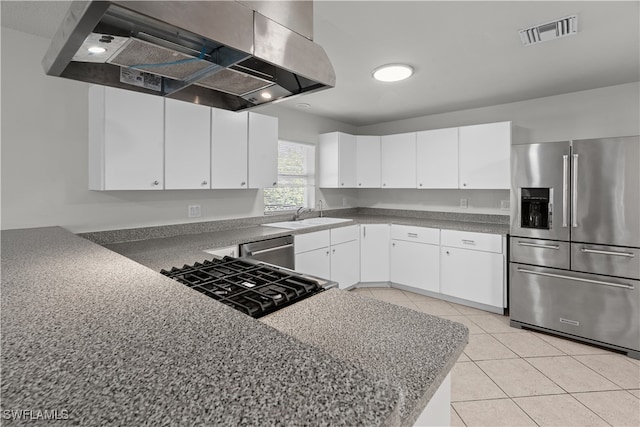 kitchen featuring light tile patterned floors, a sink, visible vents, wall chimney range hood, and appliances with stainless steel finishes