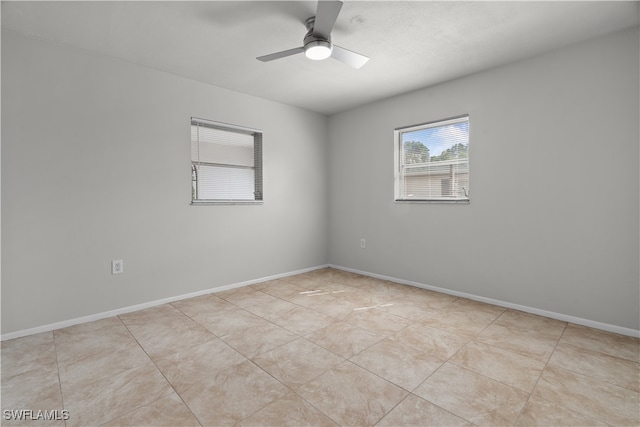 tiled spare room with ceiling fan and baseboards