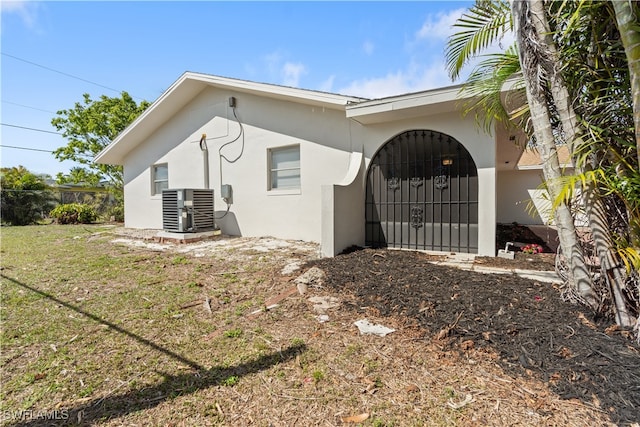 view of property exterior featuring a yard, central AC unit, and stucco siding