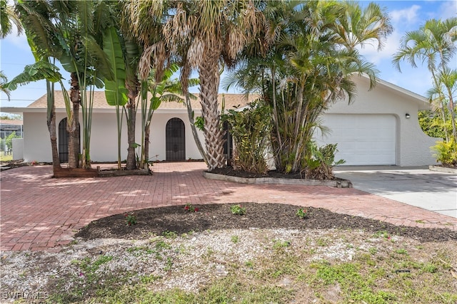 view of front of house with a garage, decorative driveway, and stucco siding