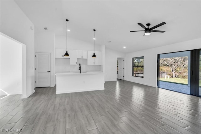 unfurnished living room featuring a sink, baseboards, and wood finished floors