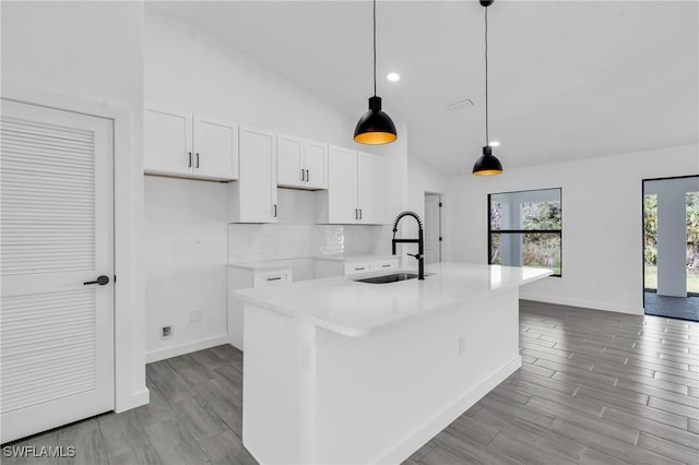 kitchen with light wood finished floors, a sink, a kitchen island with sink, and white cabinets