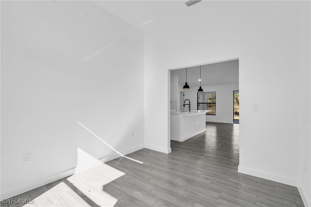 spare room with wood tiled floor, a sink, and baseboards