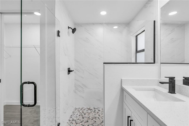 bathroom with a stall shower, recessed lighting, a spacious closet, and vanity