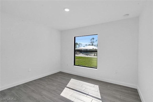 spare room featuring recessed lighting, baseboards, and wood finished floors