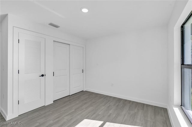 unfurnished bedroom with a closet, baseboards, visible vents, and light wood finished floors