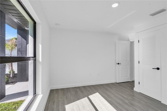 spare room featuring wood finished floors, visible vents, and baseboards