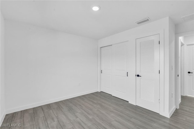 unfurnished bedroom featuring recessed lighting, visible vents, baseboards, and wood finished floors