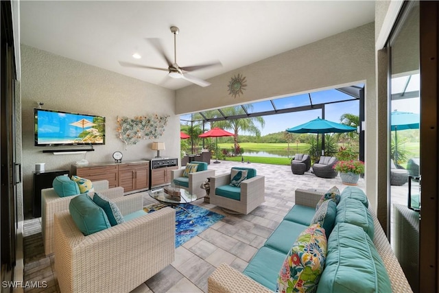 living area featuring ceiling fan, a textured wall, and a sunroom