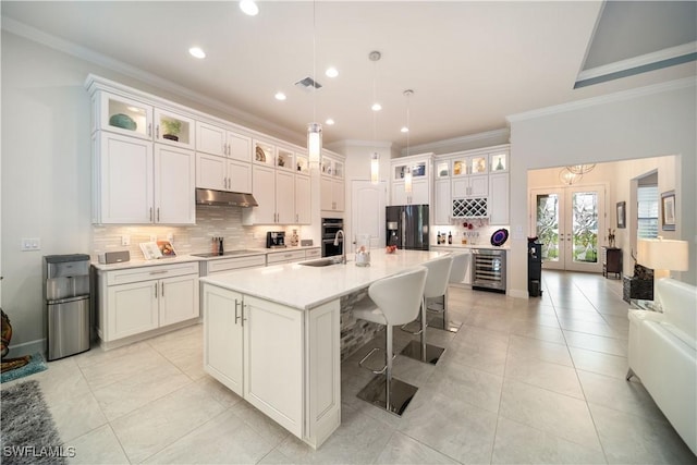 kitchen with black electric stovetop, french doors, under cabinet range hood, refrigerator with ice dispenser, and a sink