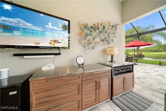 kitchen featuring brown cabinets, a water view, and a textured wall