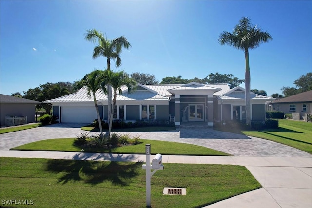 single story home featuring a garage, metal roof, a standing seam roof, french doors, and a front yard