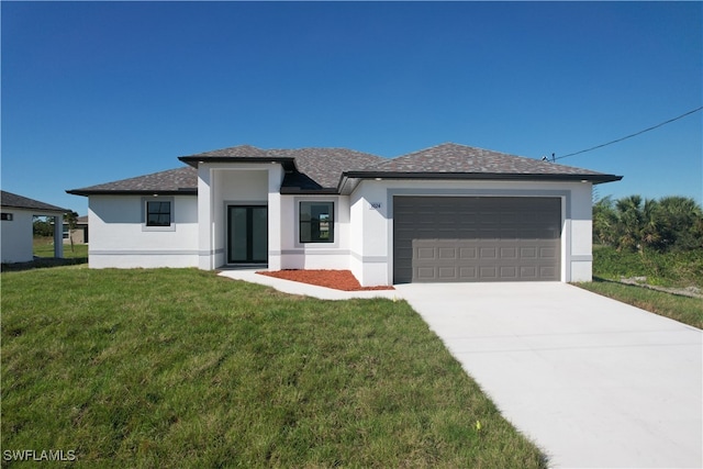 prairie-style home featuring a garage, concrete driveway, a front yard, and stucco siding