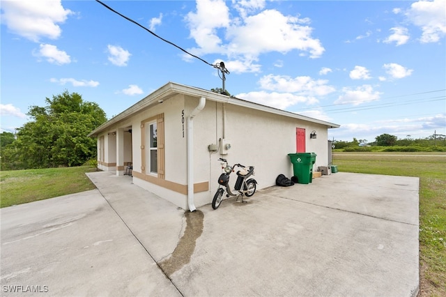 5011 Dania Cir, Labelle, FL 33935 - view of side of home featuring a yard, a patio, and stucco siding