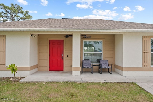 entrance to property with stucco siding, a porch, and roof with shingles