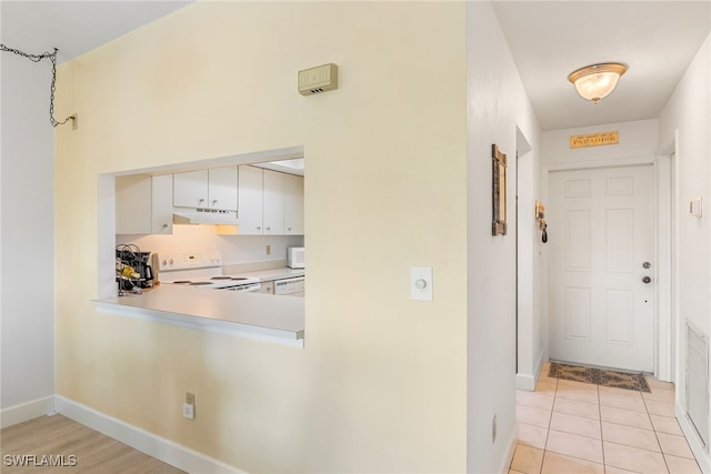 kitchen featuring light tile patterned floors, light countertops, white cabinetry, white appliances, and under cabinet range hood