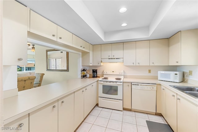 kitchen with white appliances, under cabinet range hood, light countertops, and cream cabinetry