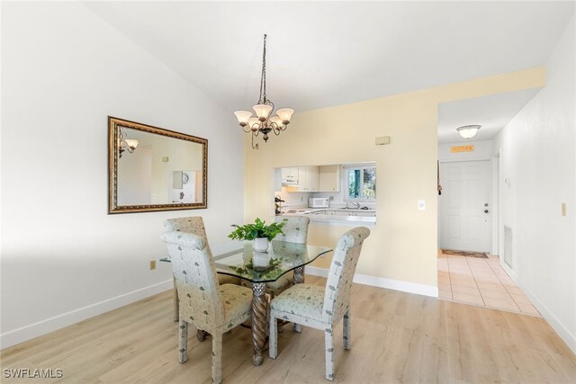 dining area featuring light wood-style flooring, vaulted ceiling, visible vents, and a chandelier