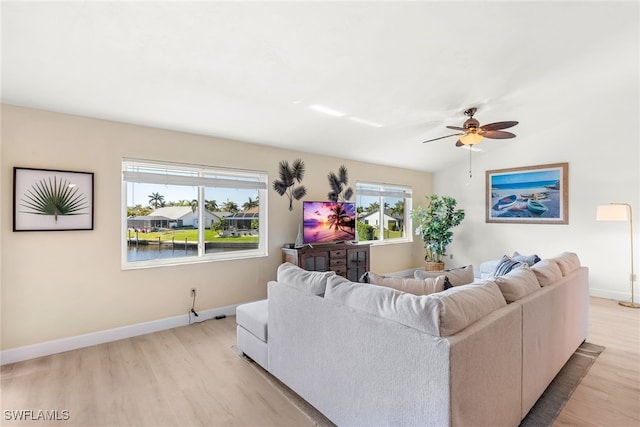 living area with vaulted ceiling, light wood finished floors, and baseboards