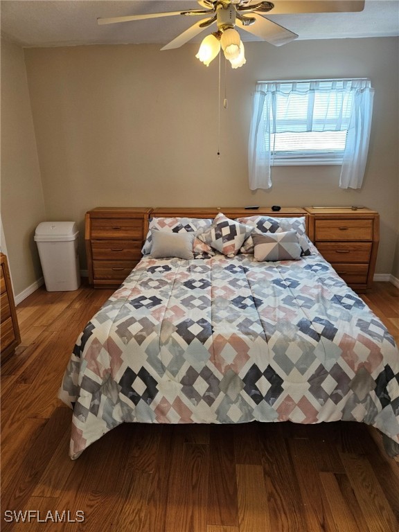 bedroom featuring a ceiling fan, baseboards, and wood finished floors