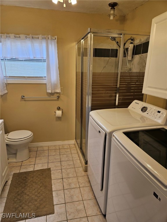 washroom featuring light tile patterned floors, baseboards, independent washer and dryer, and laundry area