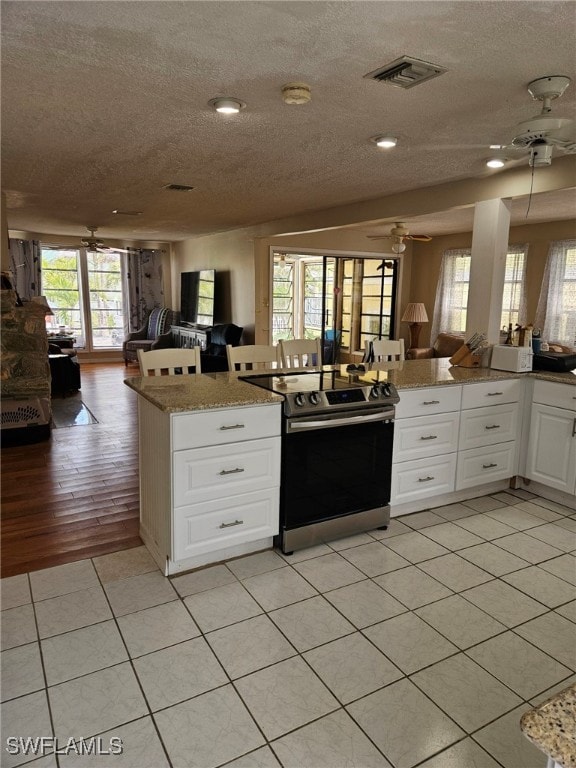 kitchen featuring open floor plan, visible vents, stainless steel electric range, and ceiling fan