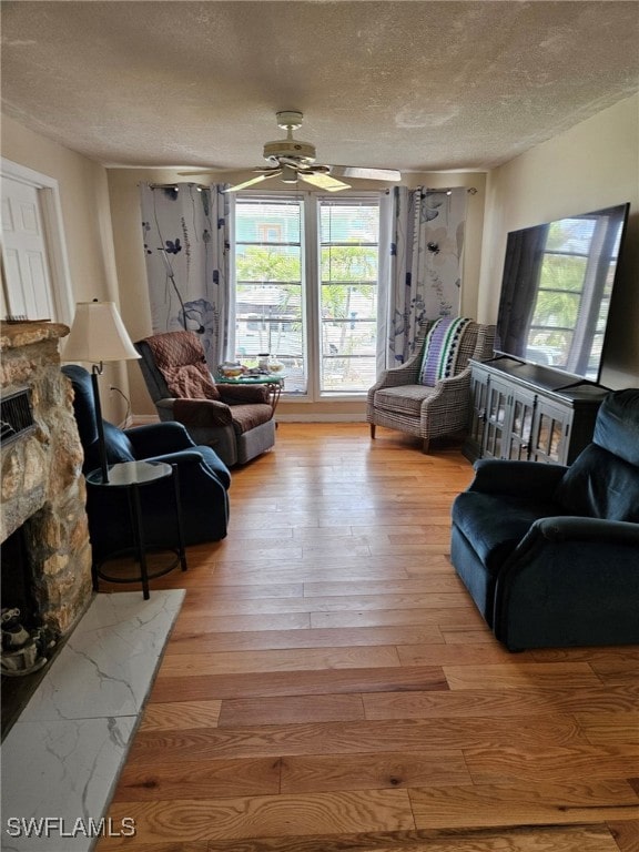 living area featuring a wealth of natural light, a fireplace, and wood finished floors