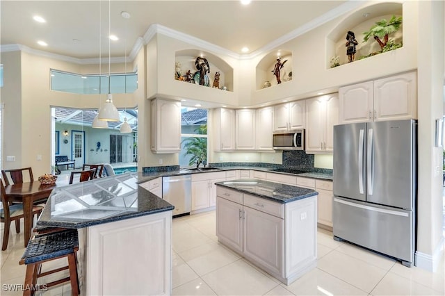 kitchen featuring appliances with stainless steel finishes, ornamental molding, a peninsula, and a towering ceiling