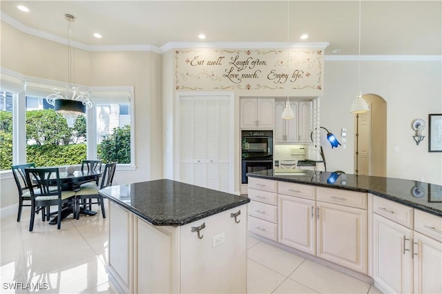 kitchen with arched walkways, a center island, crown molding, and hanging light fixtures