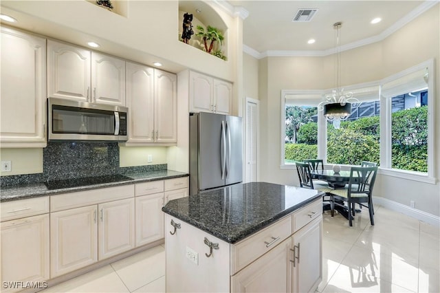 kitchen featuring visible vents, appliances with stainless steel finishes, ornamental molding, dark stone countertops, and decorative light fixtures