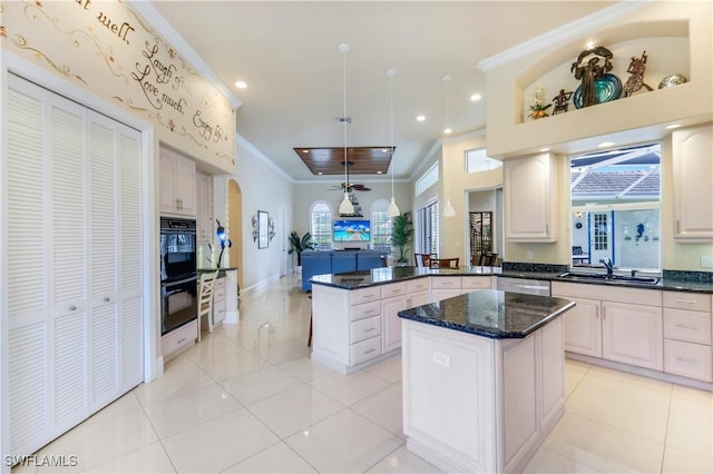 kitchen with dobule oven black, a peninsula, a sink, a ceiling fan, and ornamental molding