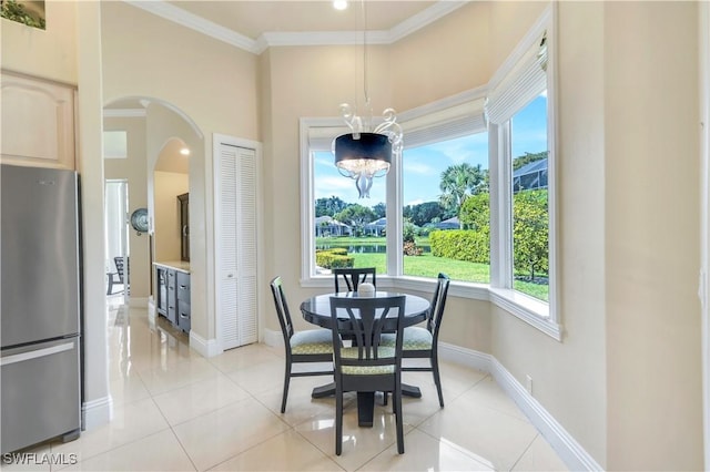 dining space with arched walkways, light tile patterned floors, ornamental molding, a chandelier, and baseboards