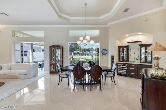 dining area with beverage cooler, visible vents, ornamental molding, a raised ceiling, and an inviting chandelier