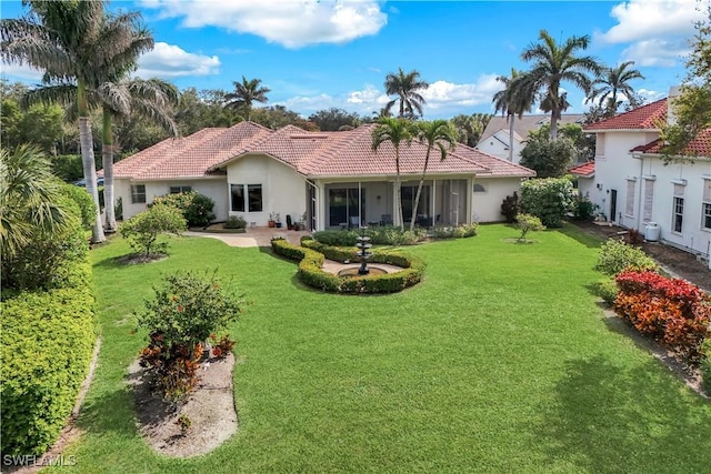 rear view of property featuring a lawn, stucco siding, and a tiled roof