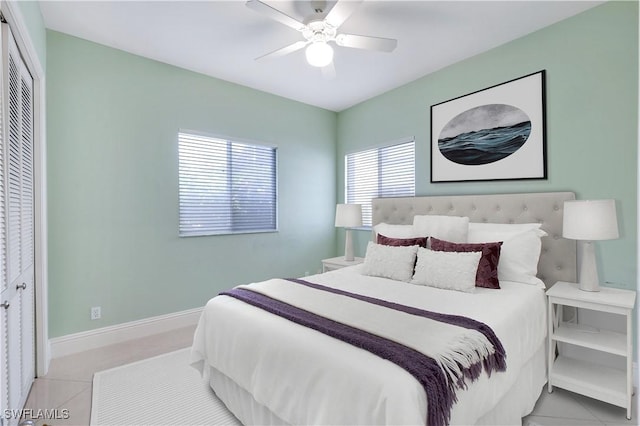 bedroom with light tile patterned floors, baseboards, ceiling fan, and a closet