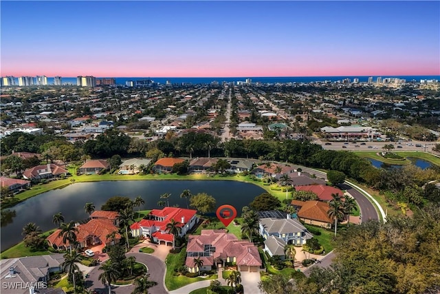 aerial view at dusk with a water view and a residential view