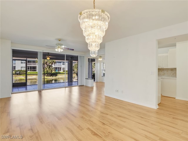 empty room with light wood-type flooring, baseboards, and ceiling fan with notable chandelier