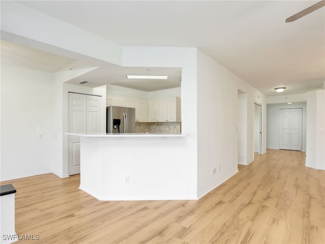 kitchen with light wood-style flooring, white cabinetry, decorative backsplash, and stainless steel fridge with ice dispenser