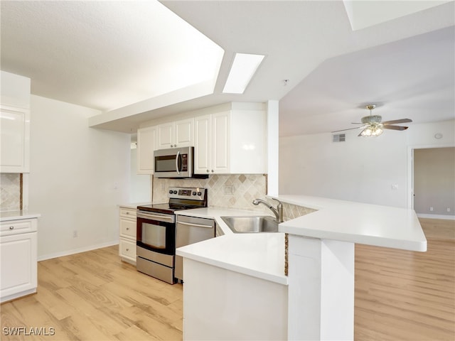 kitchen featuring visible vents, appliances with stainless steel finishes, white cabinets, a sink, and a peninsula