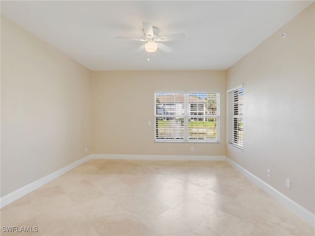 spare room with ceiling fan and baseboards